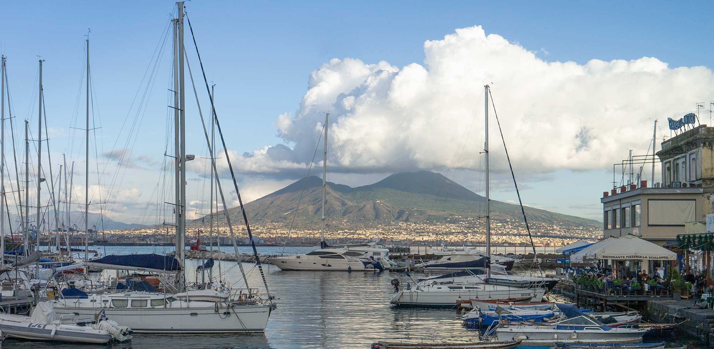 Boote liegen am Golf von Neapel im Hintergrund der Vulkan Vesuv.